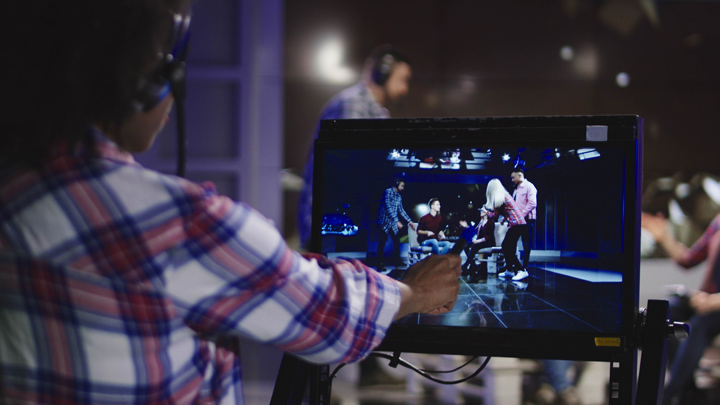 A person pointing to a monitor on a television studio